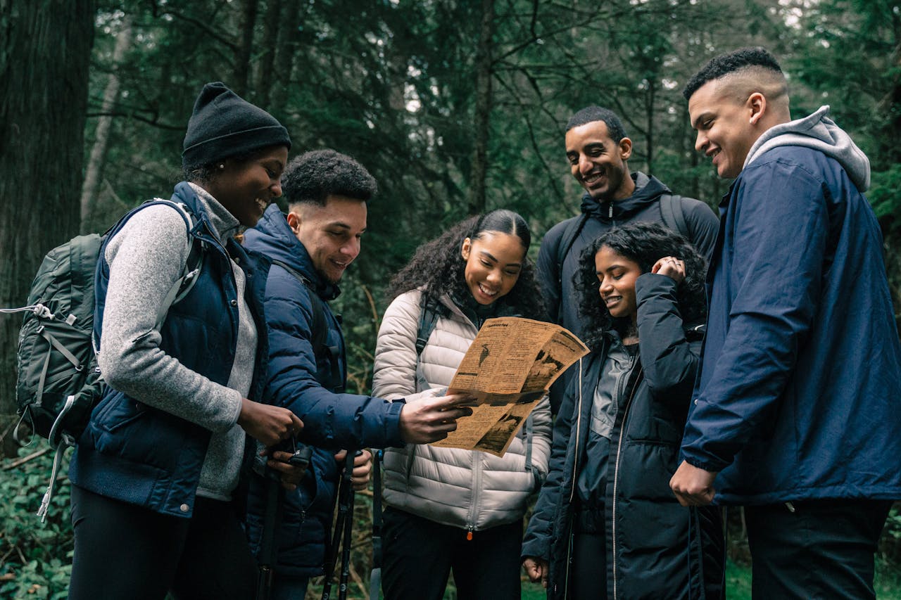 Diverse group of friends hiking together, planning their adventure in a lush forest.